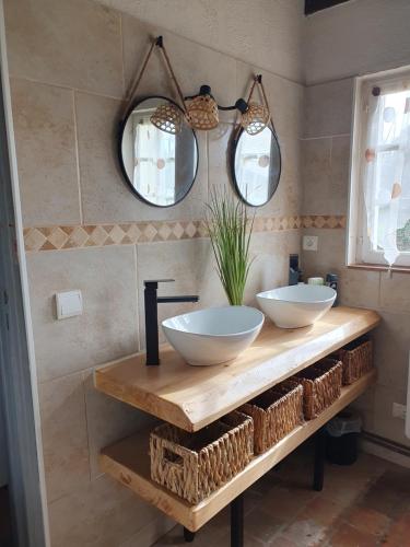 two sinks on a counter in a bathroom with mirrors at Gite les Bruyères in Salbris