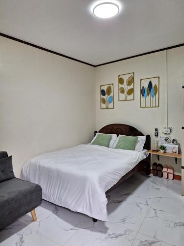 a bedroom with a large white bed and a couch at G & B Transient House in San Jose