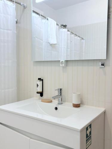 a white bathroom with a sink and a mirror at Casa Conceição in Ribeira Brava