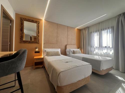 a hotel room with two beds and a desk and a mirror at ND Hoteles in Valdemoro