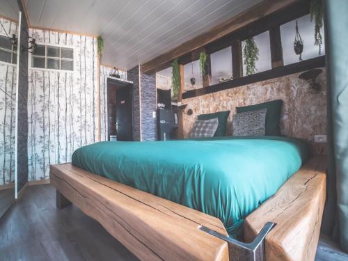 a bedroom with a wooden bed with a green comforter at Domaine des 7 cépages in Arsonval