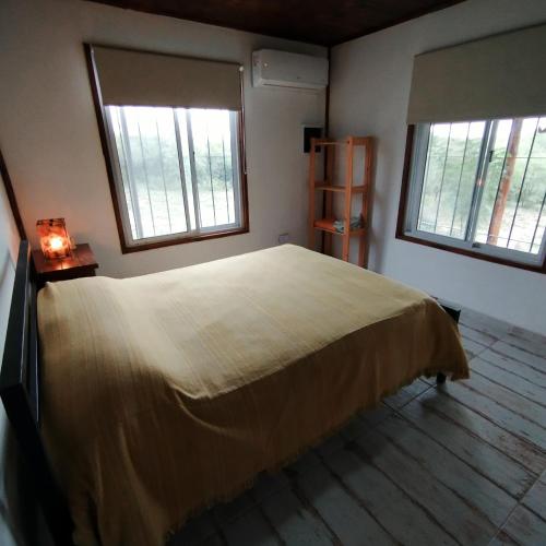 a bedroom with a large bed and two windows at Entre Tanto in Luyaba