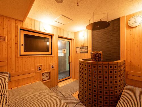 a living room with a television and a clock on the wall at 2025 RENEWAL OPEN Anshin oyado Nagoya Man & Woman Sakae Station in Nagoya