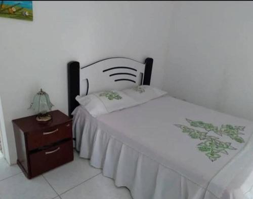 a bedroom with a white bed and a wooden nightstand at Dunas de Guarajuba in Camacari