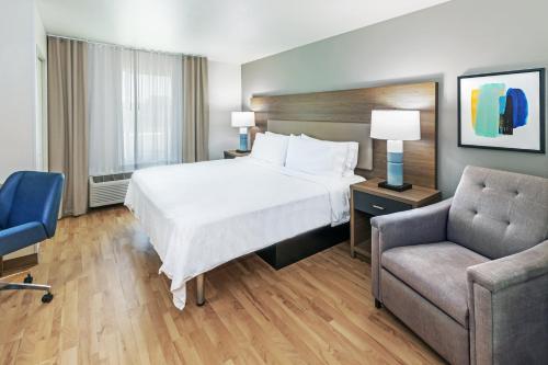 a hotel room with a bed and a chair at Candlewood Suites - Muskogee by IHG in Muskogee
