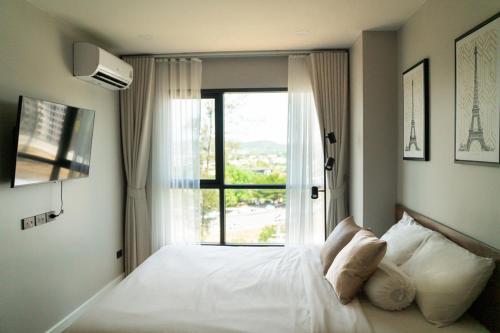 a bedroom with a white bed with a window at Comfortable 2Bdr Bangtao Space Condo in Ban Thalat Choeng Thale