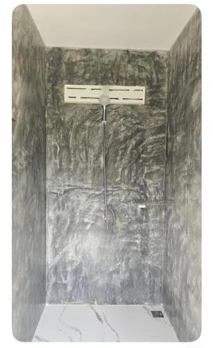 a shower in a room with a stone wall at Namosototie in Ranong