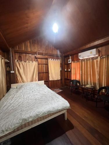 a bedroom with a bed in a wooden house at Namosototie in Ranong