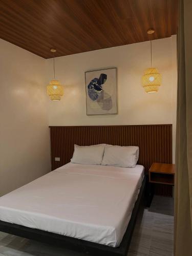 a bed in a bedroom with two lights on the wall at Casa Sereno Spring Resort in Irosin