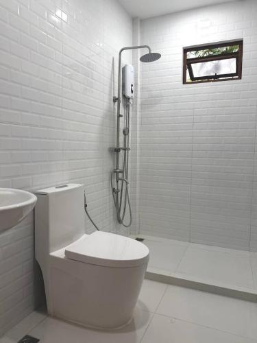 a white bathroom with a toilet and a shower at Casa Sereno Spring Resort in Irosin