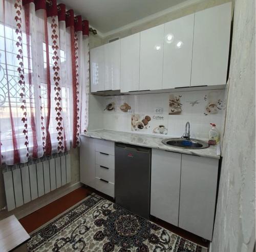 una piccola cucina con mobili bianchi e un lavandino di Квартира a Karakol