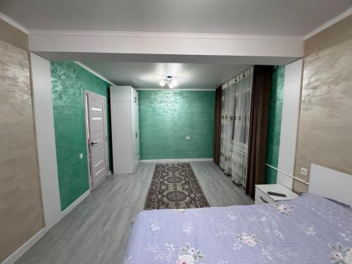 una stanza con un letto e una parete verde di Квартира a Karakol