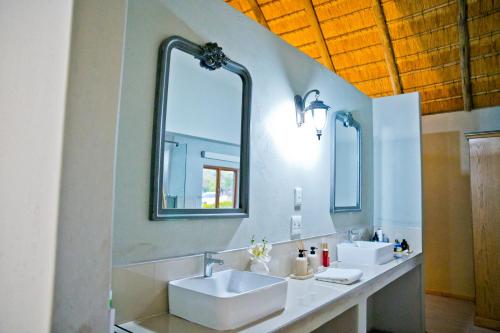 a bathroom with two sinks and two mirrors at Collen Pillar Hotels, Windsor Royale in Athol