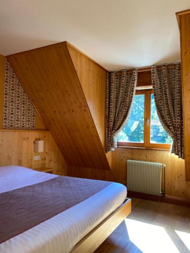 a bedroom with a bed and a large window at LE CLOS DES SOURCES Hôtel & Spa in Thannenkirch