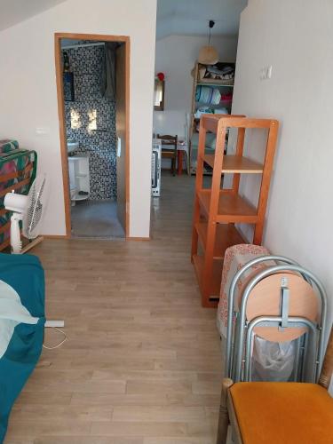 a living room with a wooden floor and a room with a chair at Studio apartman u ruralnom okruženju in Donji Karin