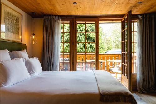 a bedroom with a large bed and a balcony at L'Alpaga, a Beaumier hotel in Megève
