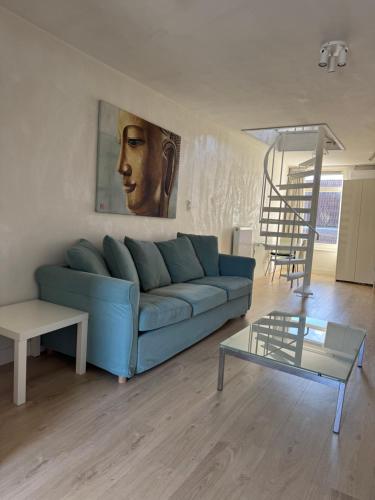 a living room with a blue couch and a staircase at Studio Jordaan Amsterdam City Centre in Amsterdam