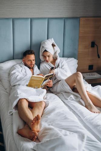 a man and woman laying in bed reading a book at Mielno Hotel Boutique in Mielno