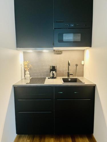 a kitchen with black cabinets and a sink at Spirit Bed & Breakfast in Ekeby