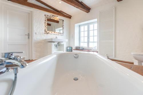 a white bath tub in a bathroom with a sink at Lodge an der Muehle in Bredstedt