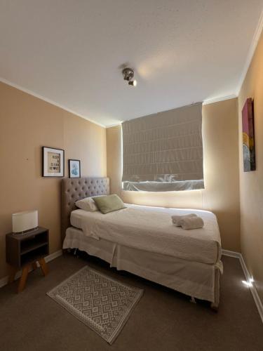 a small bedroom with a bed and a window at Cómodo departamento en Curicó in Curicó