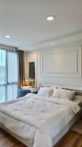 a large white bed in a room with a window at i-CONDO B2072 in Ban Liap