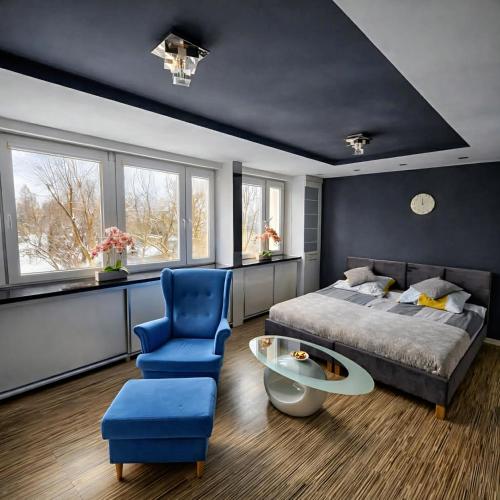 a bedroom with a bed and a blue chair and a table at Black & White Komfortowe Apartamenty 2 km od Centrum in Racibórz