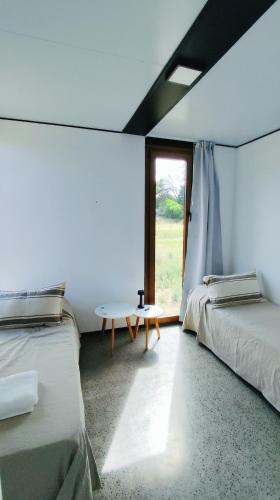 two beds in a room with a table and a window at Serena - Tini Houses - in Mar de las Pampas