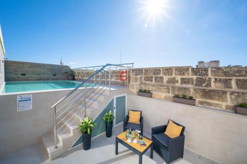 a balcony with a swimming pool and two chairs and a table at C4 Retreats Gozo in Xagħra