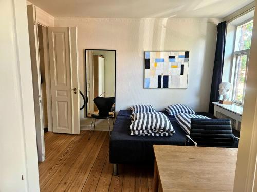 a living room with a black couch and a mirror at Charming Heritage Townhouse in Odense