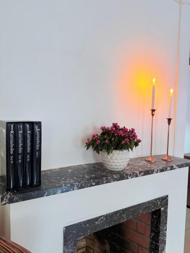 a fireplace with two candles and flowers on it at Kungsbacken Hotell & Konferens in Katrineholm