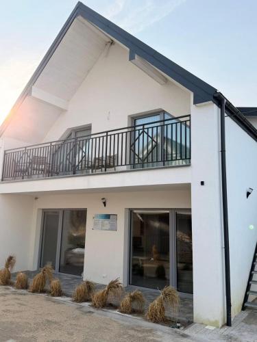 a white building with a balcony and windows at Apartament Paula SPA Niechorze in Niechorze