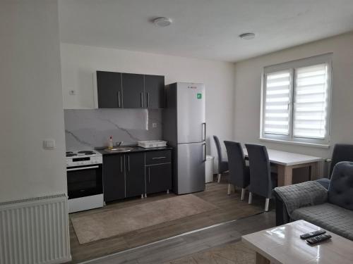 a kitchen with a refrigerator and a table with chairs at Apartman Iva in Foča