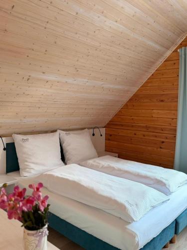 a bed in a room with a wooden ceiling at Białe Domki Paula SPA Niechorze in Niechorze