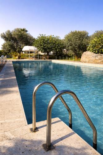 a swimming pool with a metal hand rail next to it at Isola Charm B&B - Pool & Nature Stay in Syracuse