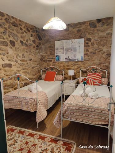 a bedroom with two beds and a stone wall at Casa do Sobrado-Gralhas-Montalegre in Gralhas