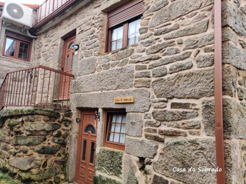 a stone building with a wooden door and windows at Casa do Sobrado-Gralhas-Montalegre in Gralhas