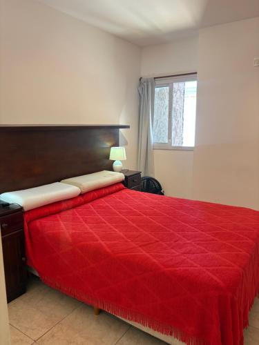 a bedroom with a red bed with a red comforter at Amelia 2-1 in Villa Carlos Paz