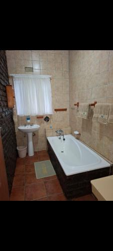 a bathroom with a bath tub and a sink at Eagles guest house Piet Retief in Piet Retief