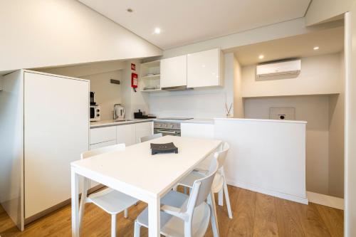 a white kitchen with a white table and chairs at Terro Collection - Alcaide in Braga
