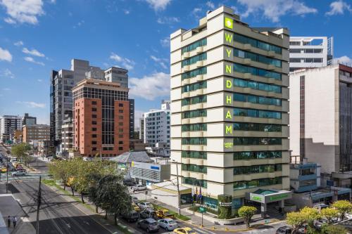 a tall white apartment building in a city at Wyndham Garden Quito in Quito