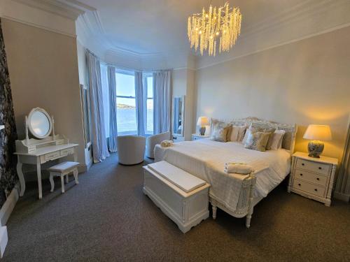 a bedroom with a large bed and a chandelier at The Harbour House - Deluxe Town Centre Property in Rothesay