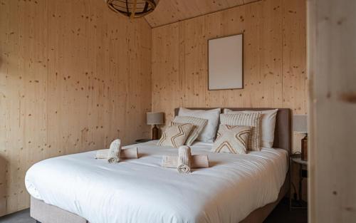 a large white bed in a room with wooden walls at Tinyhouse luxe met privé hottub in Meerssen