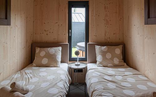 two beds sitting in a room with a window at Tinyhouse luxe met privé hottub in Meerssen