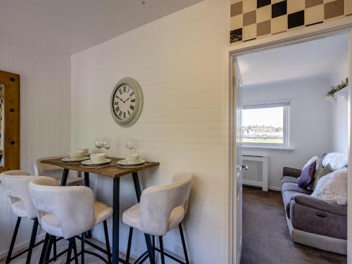 a dining room with a table and chairs and a clock at Sunrise Cottage in Berwick-Upon-Tweed