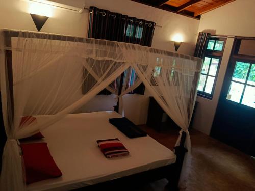 a bedroom with a bed with white mosquito netting at Monkey villa in Hikkaduwa