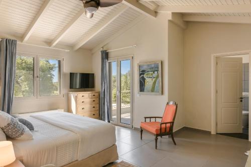 a bedroom with a bed and a chair and windows at Villa Felicity in Svoronata