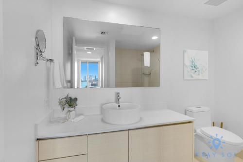 a white bathroom with a sink and a mirror at Beachwalk Condo in Hallandale Beach
