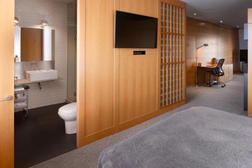 a bathroom with a toilet and a tv on a wall at Hotel Gault in Montreal