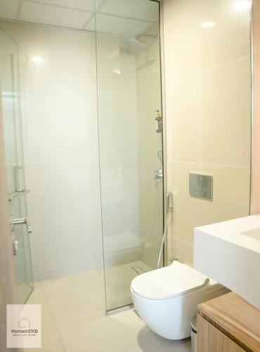 a bathroom with a toilet and a glass shower at Elegant Haven by Meraki - New 1 Bed Garden View in Dubai